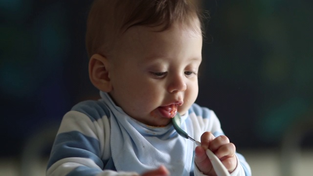 可爱的婴儿幼儿咬勺子。父母喂养快乐的婴儿宝宝视频素材