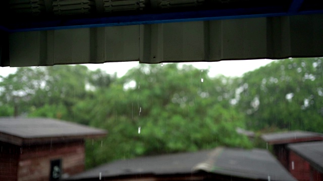 雨从屋顶落下的慢镜头，背景是木屋和树木视频素材