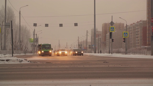 冬季城市的汽车和公共汽车行驶在积雪的高速公路交汇处。汽车行驶在城市积雪的十字路口。城市公路冬季十字路口。视频素材