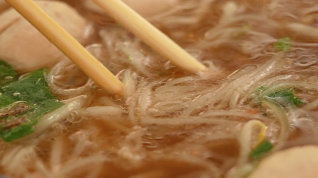 在传统的越南牛肉汤越南河粉中，用筷子挑面条。越南风格的食物。视频素材