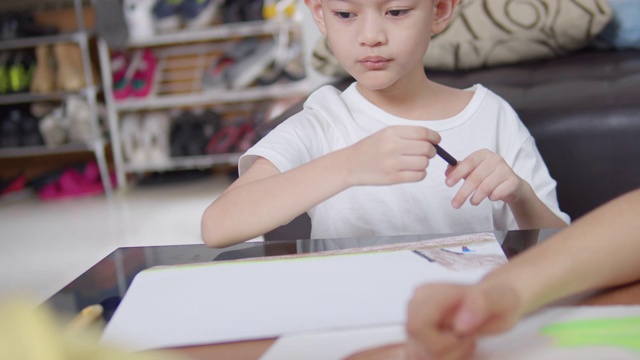 两个男孩和女孩呆在家里，在客厅用手指画画，画艺术和工艺。他们用蜡笔或粉笔的颜色在纸上创造艺术项目，形成她的想象。艺术和工艺概念视频素材