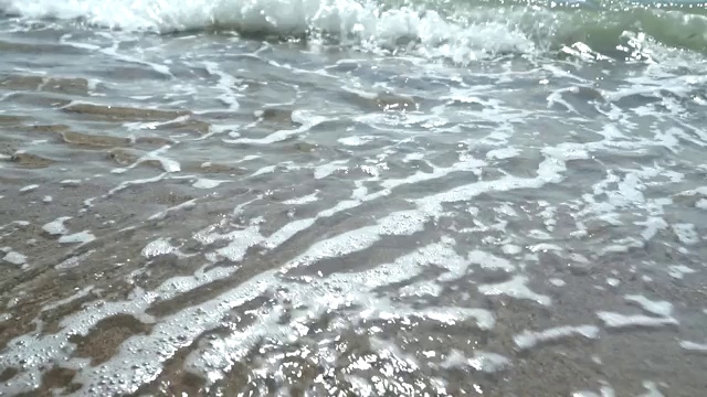 海滩，泡沫的海洋，海浪冲刷着沙子。海浪冲击着沙滩。海浪声视频素材