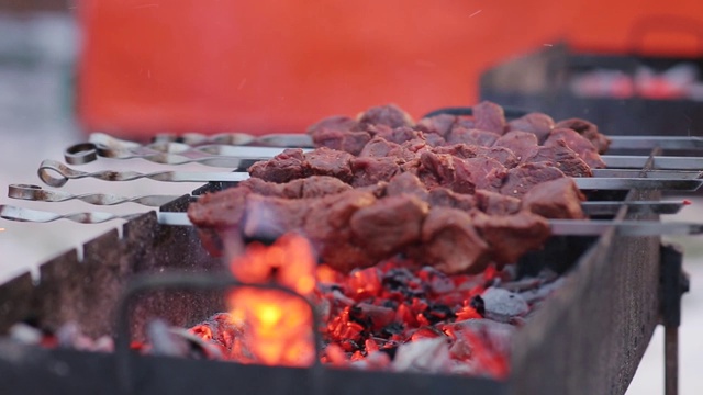 用串烤肉，把烤好的肉放在烤架上。冬天在煤块上放一块猪肉。在户外用芒果做烤肉串视频素材