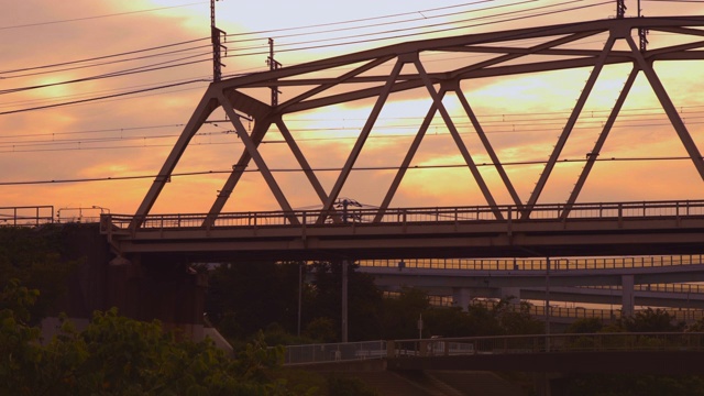 一列沐浴在夕阳中的火车穿过横滨郊区的一座铁路桥视频素材