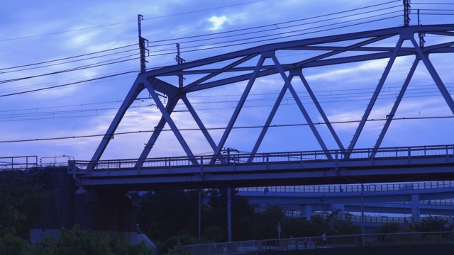 一列沐浴在夕阳中的火车穿过横滨郊区的一座铁路桥视频素材