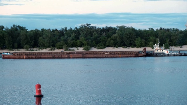 沿河岸漂浮在河上的驳船。前景的红色浮标视频素材