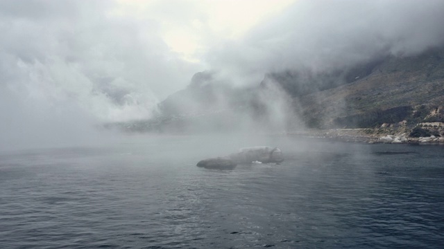 航空跟踪拍摄靠近海洋海岸线和迷雾背后的山脉视频素材