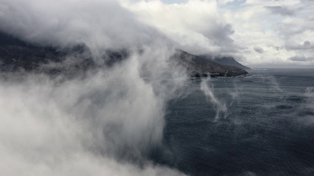 郁郁葱葱的山腰背后的浓雾和涟漪的海水在前景视频素材