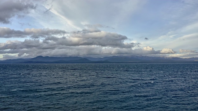 无人机拍摄的深蓝的海，多云的天空和山景视频素材