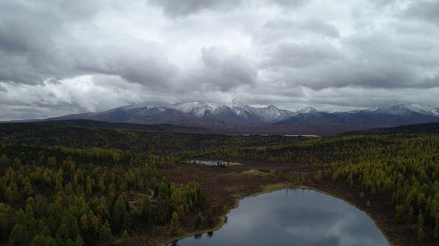 美丽明亮的森林在地平线雪山石峰。Top全景苍蝇没有人在农村植物。旅游目的地田园风光。傍晚烟雾戏剧性的天空和宁静的池塘宽拍摄4k视频素材