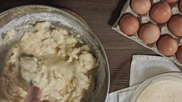 男人的手揉面团。制作美味佳肴或甜点的过程在桌子上烘焙的原料。在烹饪时，最好安排一张木桌。视频素材