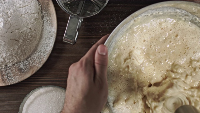 男人的手揉面团。制作美味佳肴或甜点的过程在桌子上烘焙的原料。在烹饪时，最好安排一张木桌。视频素材