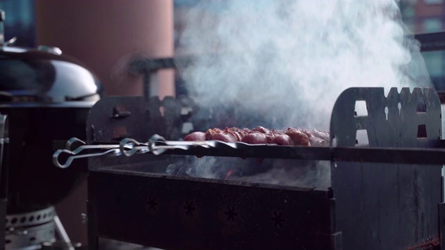 在露台上进行烧烤野餐，男人们在烧烤架上烤各种各样的肉串，将肉串翻转以便更好地烧烤。用香料和香料炒的肉。户外烧烤和放松视频素材