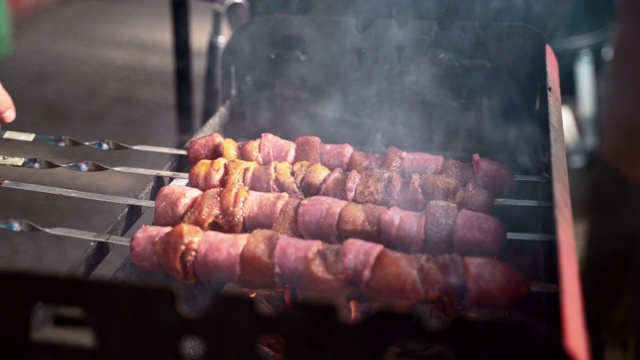 人的手在户外烧烤生肉，烹饪肉类烧烤在加热木炭烧烤野餐。烤肉架上放着腌制过的烤肉串，男子正在为户外野餐准备食物视频素材