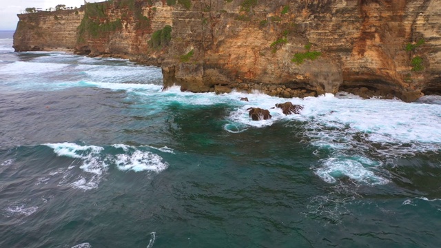 Uluwatu巴厘岛。蓝色的海洋和岩石山，覆盖着热带树木。视频素材