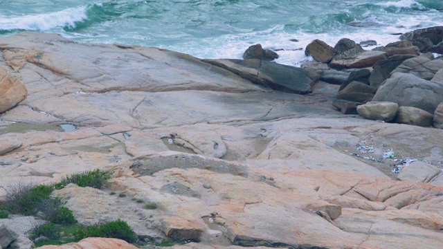 多岩石的海岸，有巨石和大石头。海浪溅起白色的浪花和巨大的水珠在潮湿的石滩上视频素材