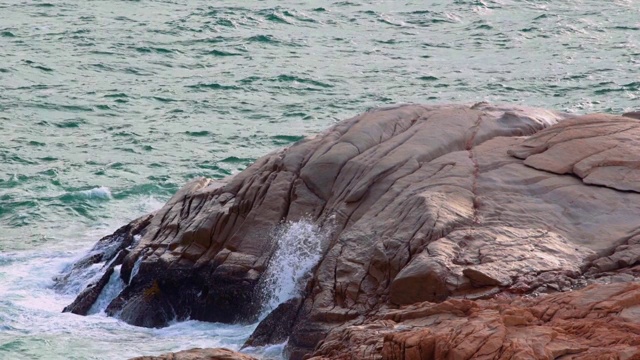 巨大的海浪拍打着岩石峭壁，溅起白色的泡沫。用波浪拍打着海岸的石头。4K和特写视频素材