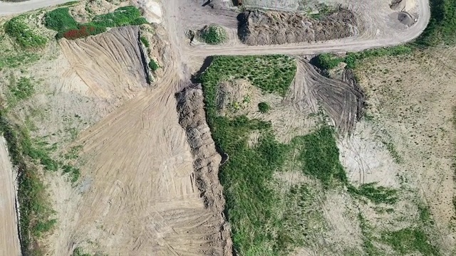 空中拍摄的一个旋转和倾斜的沙坑与视野的地平线上的乡村道路，田野，草地和森林在德国。视频素材