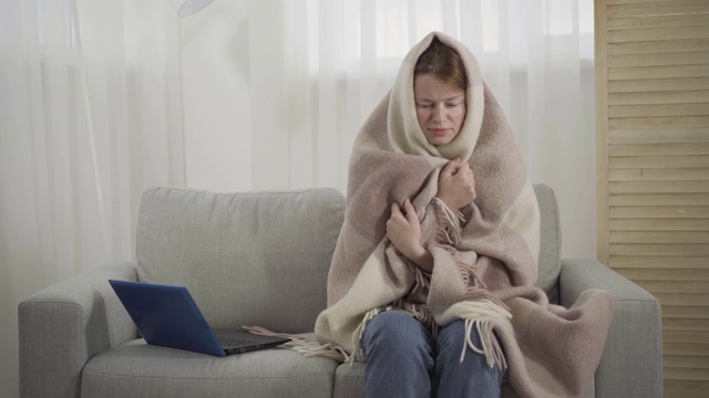 生病的白人女人打喷嚏。肖像疲惫的年轻红发女孩裹着毯子坐在沙发上发烧。医疗保健、疾病、Covid-19隔离、生活方式、药物。视频素材