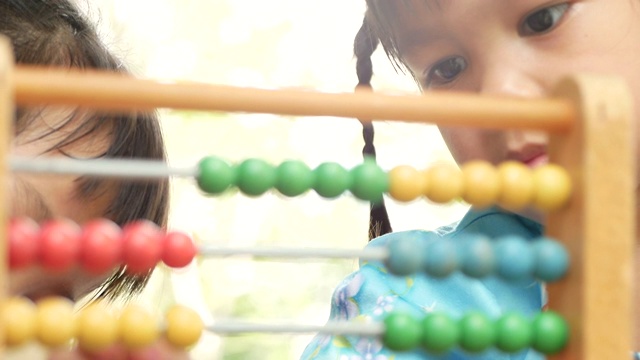 可爱的姐妹孩子女孩学习计数与教育彩色木算盘在后院。学前儿童家庭教育理念。视频素材