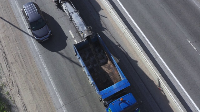 沥青碾磨将沥青表面从道路上磨碎，然后装入卡车，鸟瞰图视频素材