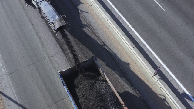 沥青碾磨将沥青表面从道路上磨碎，然后装入卡车，鸟瞰图视频下载