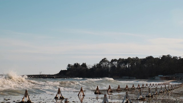 在冬季阳光明媚的日子里，巨大的海浪拍打着码头。波浪的运动与飞溅。码头的冲浪力和冲浪力。前视图视频素材