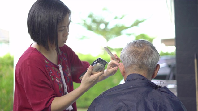 新冠肺炎大流行期间，老人在家理发，女儿在家替父亲理发视频素材