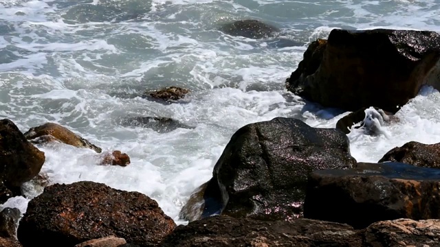 在加州旧金山的海洋海滩，海浪拍打着悬崖岩石的风景。泡沫的水，明亮的阳光视频下载