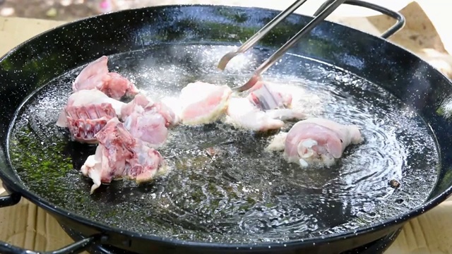 西班牙海鲜饭的制作过程，用滚烫的橄榄油在平底锅里煎兔肉视频下载