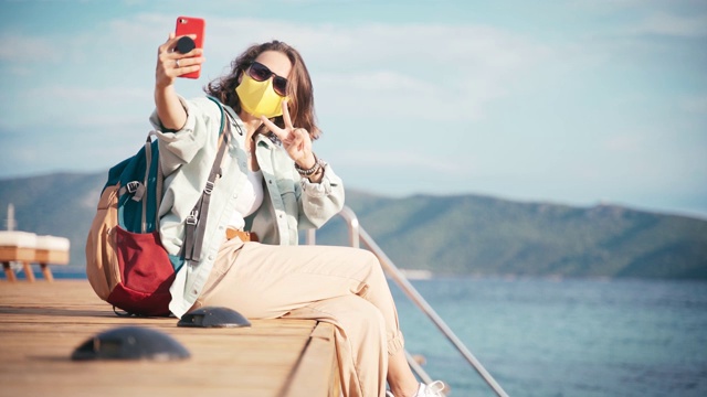 年轻女性旅行者在智能手机上自拍，这是一种新的常态旅行视频素材