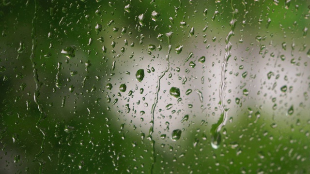 玻璃上水滴的特写，雨，雨，走开。夏天阵雨时，大雨滴打在窗玻璃上视频素材