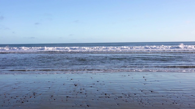 阳光明媚的日子，海浪拍打着海岸线;前景中潮湿的沙滩;Drakes海滩，Point Reyes国家海岸线，加利福尼亚视频下载