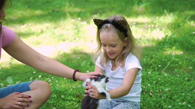 快乐的小女孩抱着可爱的小猫在户外视频素材