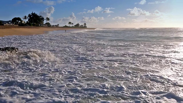 在夏威夷瓦胡岛上，海浪拍打着沙滩上一名身份确认的人视频素材