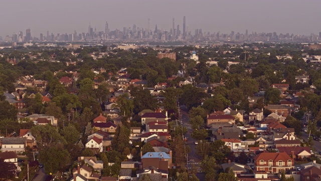 鸟瞰图的比彻斯特住宅区在皇后区与曼哈顿在日出时的远景背景。无人机视频镜头与全景相机运动视频素材