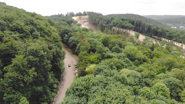 汽车在树林间的一条糟糕的道路上行驶，绕过道路上的坑洼。视频素材