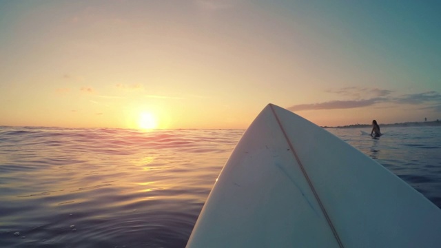 日落时，冲浪者坐在冲浪板上等待海浪。观点的冲浪视频素材