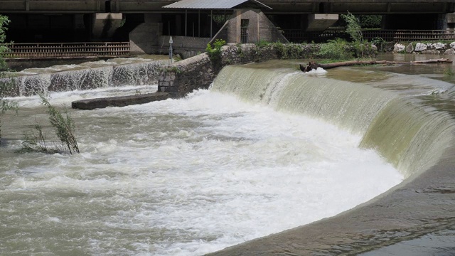 河水从屏障往下流。人们正在修建堤坝，通过控制河流的流速来减少风暴期间的侵蚀。暴雨后塞里奥河被淹视频素材