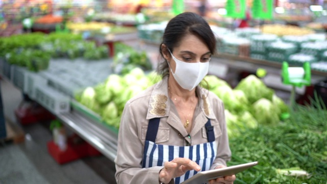 女高级超市员工或老板戴着面具使用平板电脑的肖像视频素材