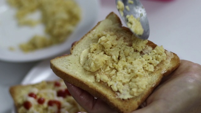 在面包上涂上黄油和炒鸡蛋视频素材