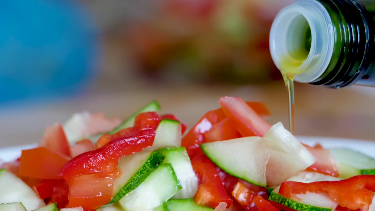 蔬菜新鲜沙拉食品健康餐地中海厨房素食饮食橄榄油。把橄榄油倒在新鲜的沙拉上。健康午餐，彩色食物洋葱黄瓜萝卜。慢动作视频素材