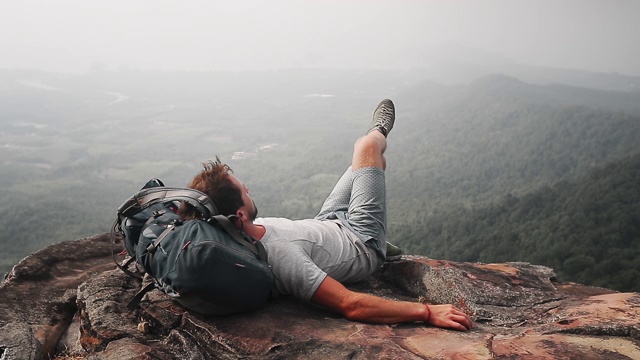 山谷风景的背包客。一名徒步旅行者用背包当枕头在山边休息视频素材