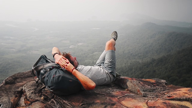 山谷风景的背包客。一名徒步旅行者用背包当枕头在山边休息视频素材