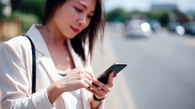 年轻女子在街上用智能手机请求和等待众包出租车视频素材