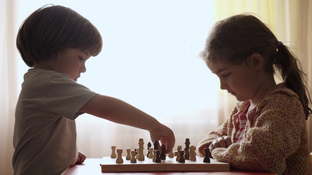 聪明的小女孩和男孩下棋的肖像。儿童与朋友在家下棋，儿童逻辑思维的发展。智力,智力。发展逻辑思维。视频素材