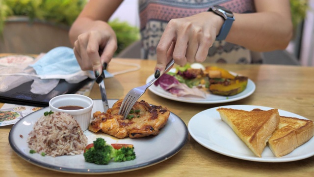 新的正常的饮食。亚洲妇女在餐厅吃午餐前摘下口罩视频素材