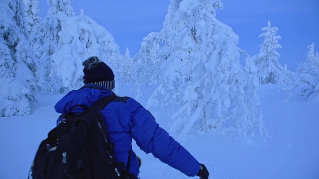 在芬兰的拉普兰地区，一个穿着蓝色冬衣的男人在没膝的雪地里行走。采用针视频素材