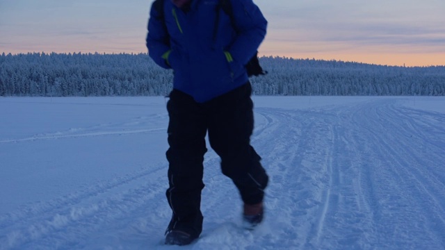 一个穿着冬衣的男人在拉普兰地区的雪地里和白雪覆盖的森林里快速行走。采用针视频素材