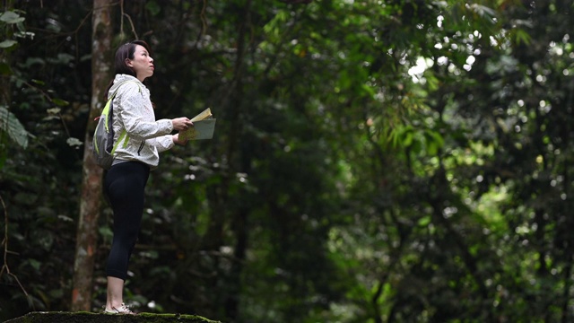 一位亚洲华裔美女在热带雨林徒步旅行路线中看着她的地图视频素材